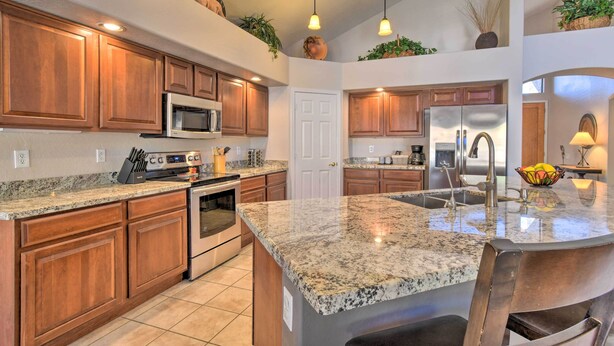 A spacious kitchen with granite countertops, wooden cabinets, stainless steel appliances, and pendant lighting. - Hot Tub & Fire Pit: Mtn-view Mesa Home! (Mesa)