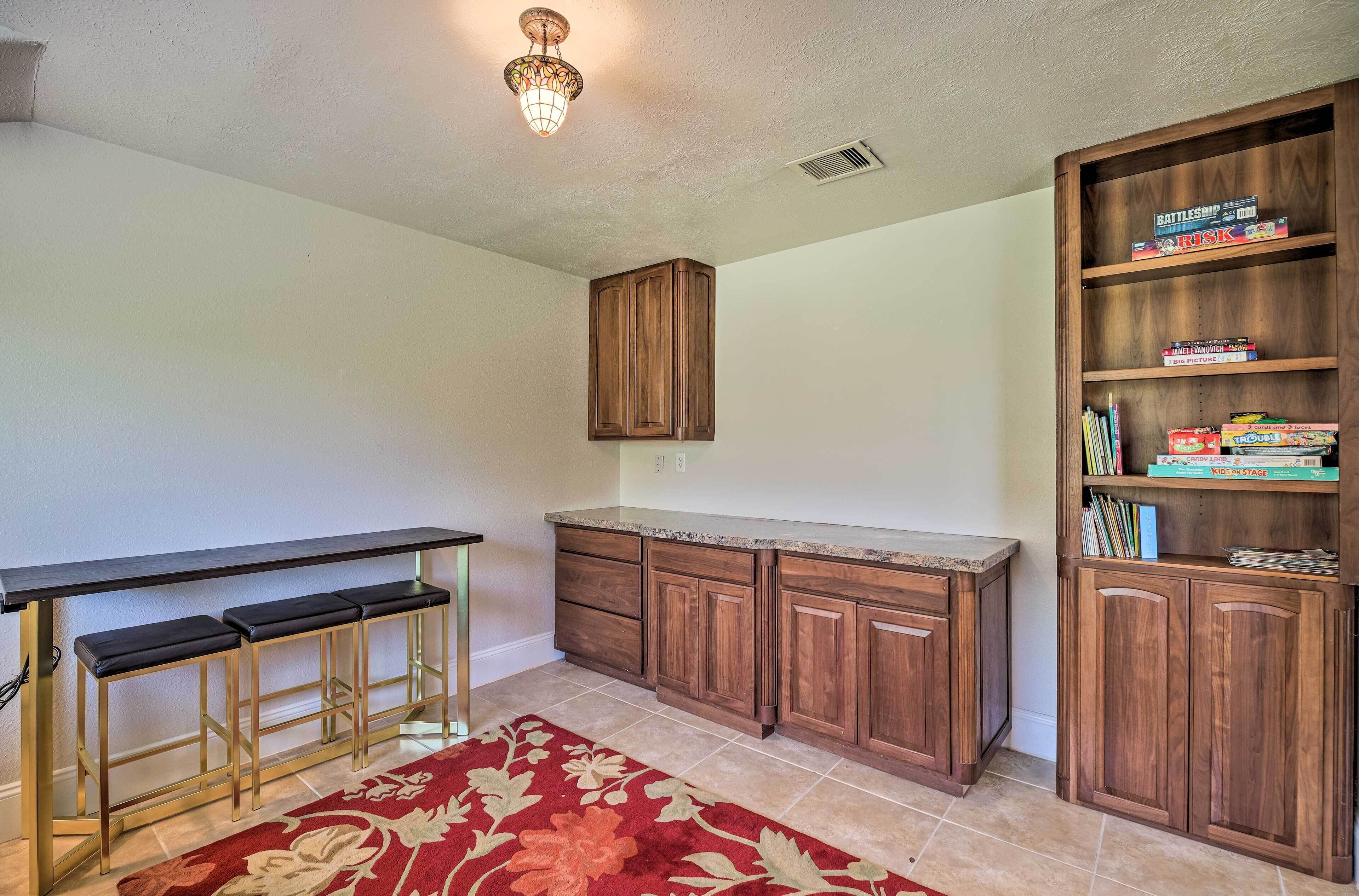 A kitchen with wooden cabinets, a countertop, and a bar area with stools.