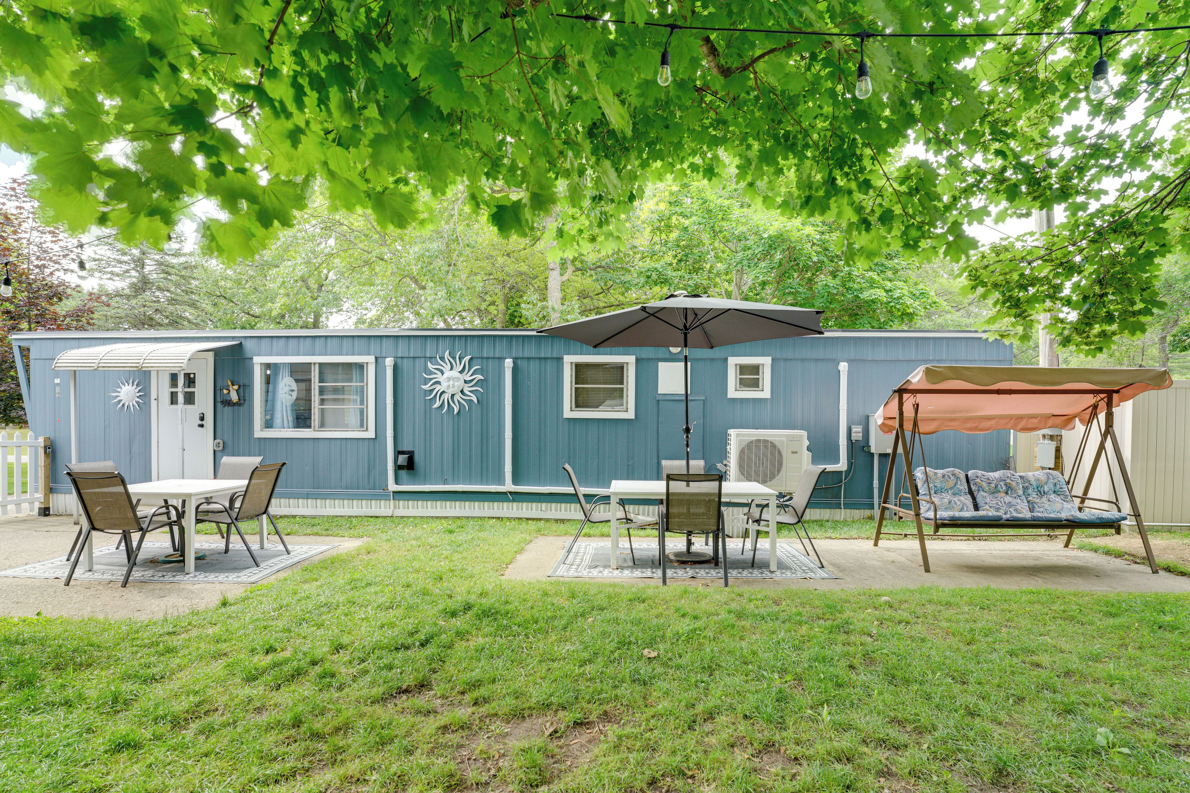 A mobile home with a patio area, a swing set, and a covered table.
