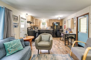 A compact living space with a kitchenette, a sofa with a cushion, a chair, and a dining table.