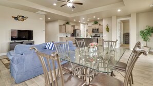 A spacious living room with a glass dining table, blue sofa, and a ceiling fan. - Modern Vacation Rental Near Zion National Park! (La Verkin)