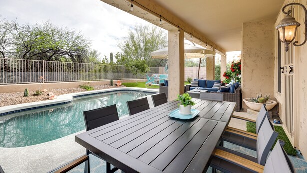 Une terrasse couverte avec une piscine, des sièges d’extérieur et une table avec des chaises.