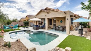 Un jardin avec une piscine, des meubles de patio et un espace extérieur aménagé avec un coin salon couvert.