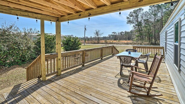A wooden deck with a table and chairs, overlooking a forested area. - Peaceful Supply House ~ 2 Mi to Holden Beach! (Supply)