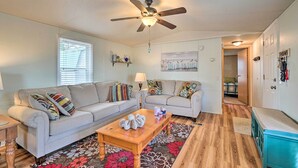 A living room with two sofas, a coffee table, a ceiling fan, and a floral rug. - Peaceful Supply House ~ 2 Mi to Holden Beach! (Supply)