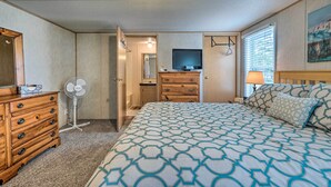 A hotel room with a bed, wooden dresser, a TV, a fan, and a painting on the wall. - Peaceful Supply House ~ 2 Mi to Holden Beach! (Supply)