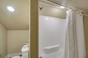 A bathroom with a white toilet, a shower stall, and a ceiling light. - 'marie's Place' - Walk to Subiaco Abbey! (Subiaco)
