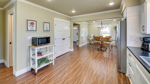 Una cocina amplia con suelo de madera, armarios blancos y una zona de comedor con candelabro.