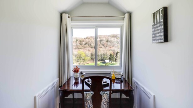A dining area with a view of a forested landscape through a large window, a dining table, and a chair. - Deck, Grill & Mountain Views: Banner Elk Retreat! (Banner Elk)