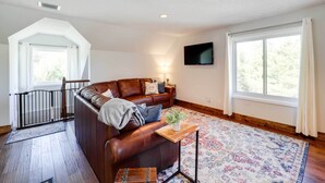 A spacious living room with a brown leather sofa, a wooden coffee table, and a patterned rug. - Deck, Grill & Mountain Views: Banner Elk Retreat! (Banner Elk)