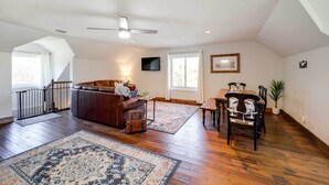 A spacious living area with hardwood flooring, a ceiling fan, a sofa, a coffee table, a dining table with chairs, and a staircase leading to an upper level. - Deck, Grill & Mountain Views: Banner Elk Retreat! (Banner Elk)