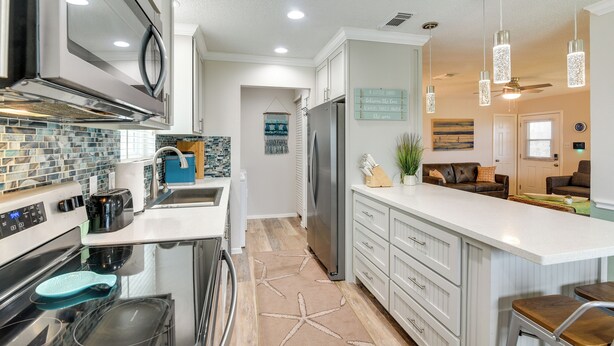 A modern kitchen with a central island, stainless steel appliances, and a backsplash with blue tiles.