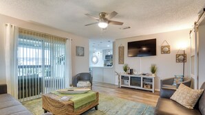 A living room with a ceiling fan, a television, and a dining area with a table and chairs.
