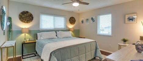 Un dormitorio con cama, mesitas de noche, ventilador de techo y adornos en la pared.