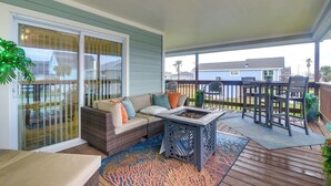 A covered patio with a wicker sofa, a fire pit, and a dining set.