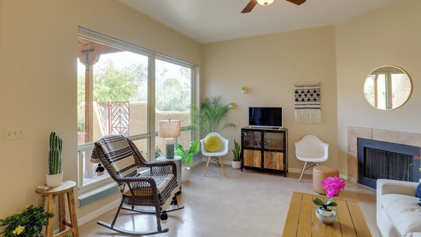 A spacious living room with a ceiling fan, a fireplace, and a large window.
