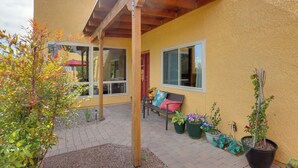 A yellow building with a covered patio area, outdoor seating, and potted plants.