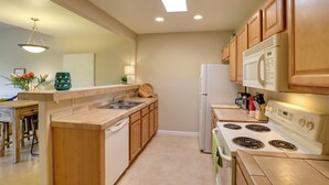 A modern kitchen with wooden cabinets, a white refrigerator, a stove, and a sink.