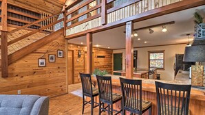 A wooden interior with a staircase, a dining area with chairs, and a kitchen area. - Piney Bluff Retreat With Mountain Views! (Melbourne)