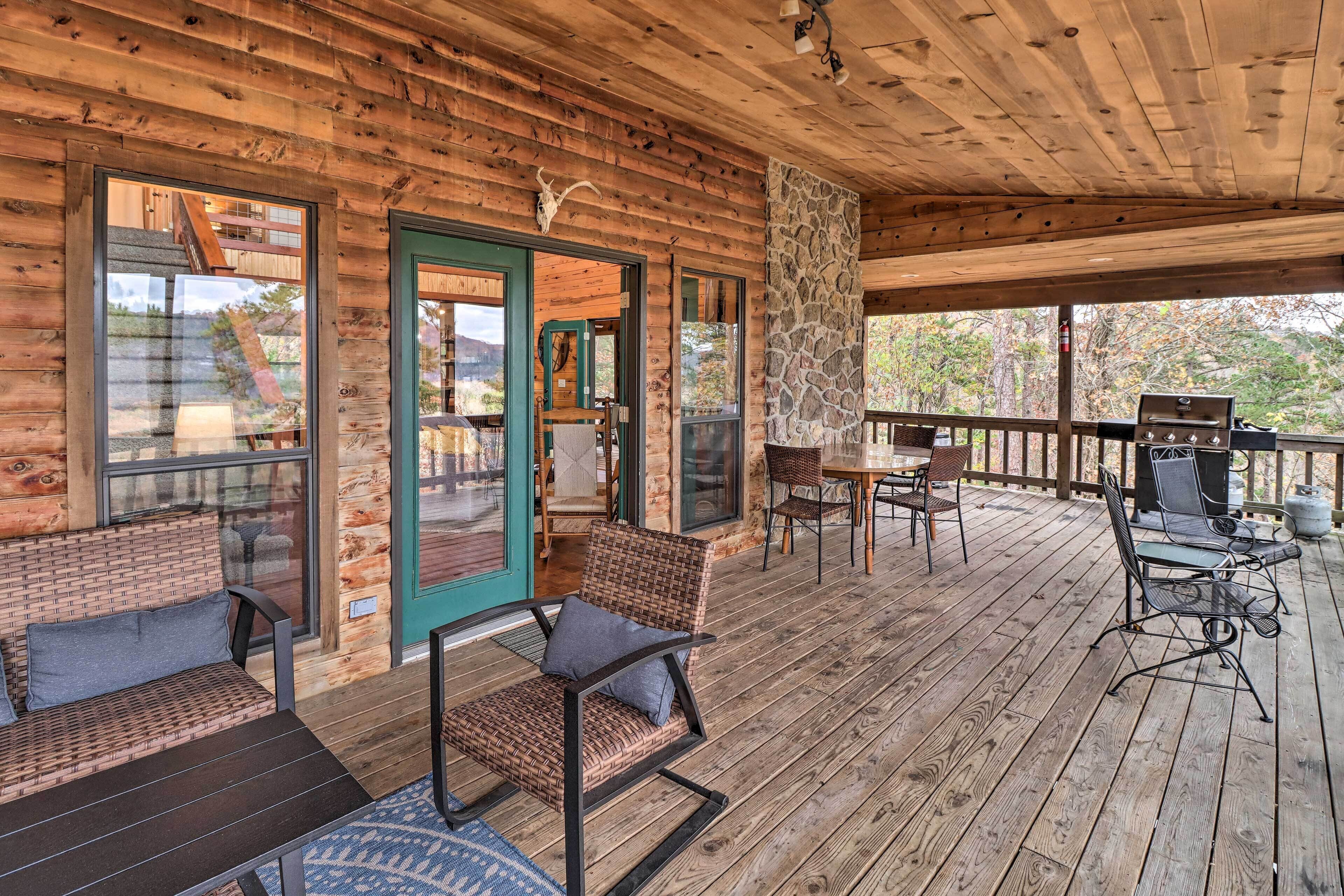 A wooden deck with outdoor seating, a stone pillar, and a grill area.