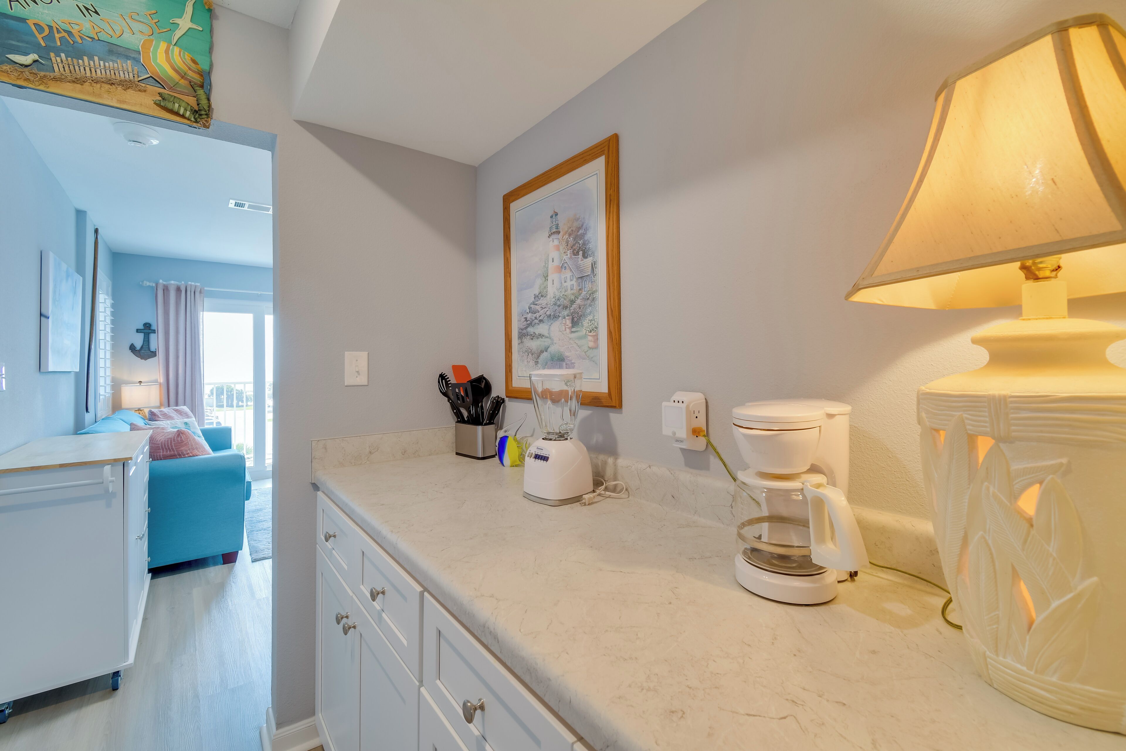 A modern kitchen with a coffee maker, blender, and a framed painting on the wall.