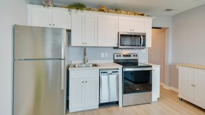 A modern kitchen with white cabinets, a stainless steel refrigerator, a dishwasher, a microwave, and an oven. - Resort Perks: Gulf Shores Beach-inspired Condo! (Gulf Shores)