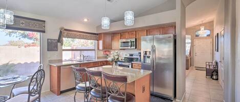 A modern kitchen with a central island, stainless steel appliances, and a dining area with bar stools.