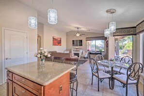 A spacious kitchen with granite countertops, a dining area with metal chairs, and a view of the outdoors. - Chandler Resort Home w/ Private Pool Near Golf (Chandler)