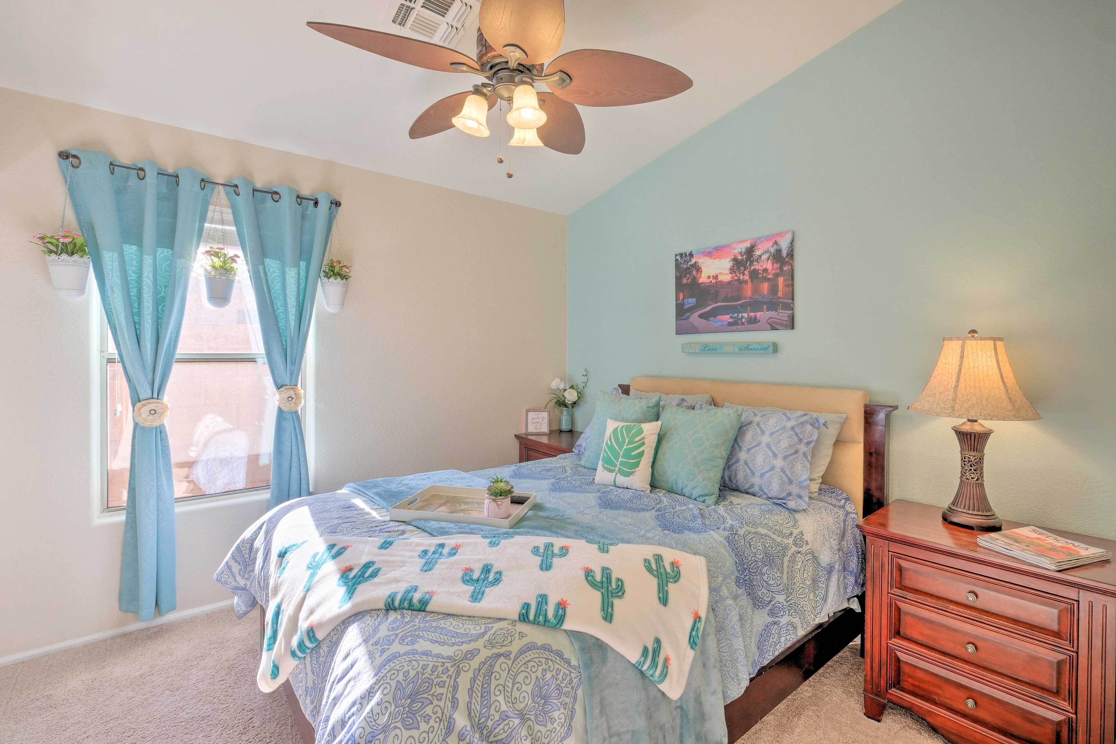 A bedroom with a bed, a nightstand, a ceiling fan, and a window with curtains.