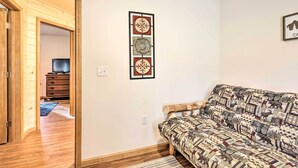 A living room with a patterned sofa, a wooden door, and a wall-mounted artwork. - Chestertown Hideaway w/ Lake & Beach Access! (Chestertown)