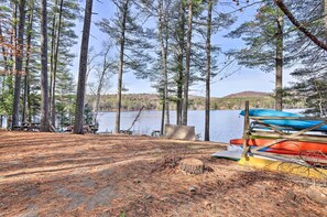 A campsite with a lake, tall trees, and a picnic table.