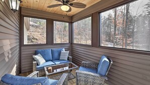A sunroom with a ceiling fan, large windows, a blue sofa, wicker chairs, and a glass coffee table. - Chestertown Hideaway w/ Lake & Beach Access! (Chestertown)
