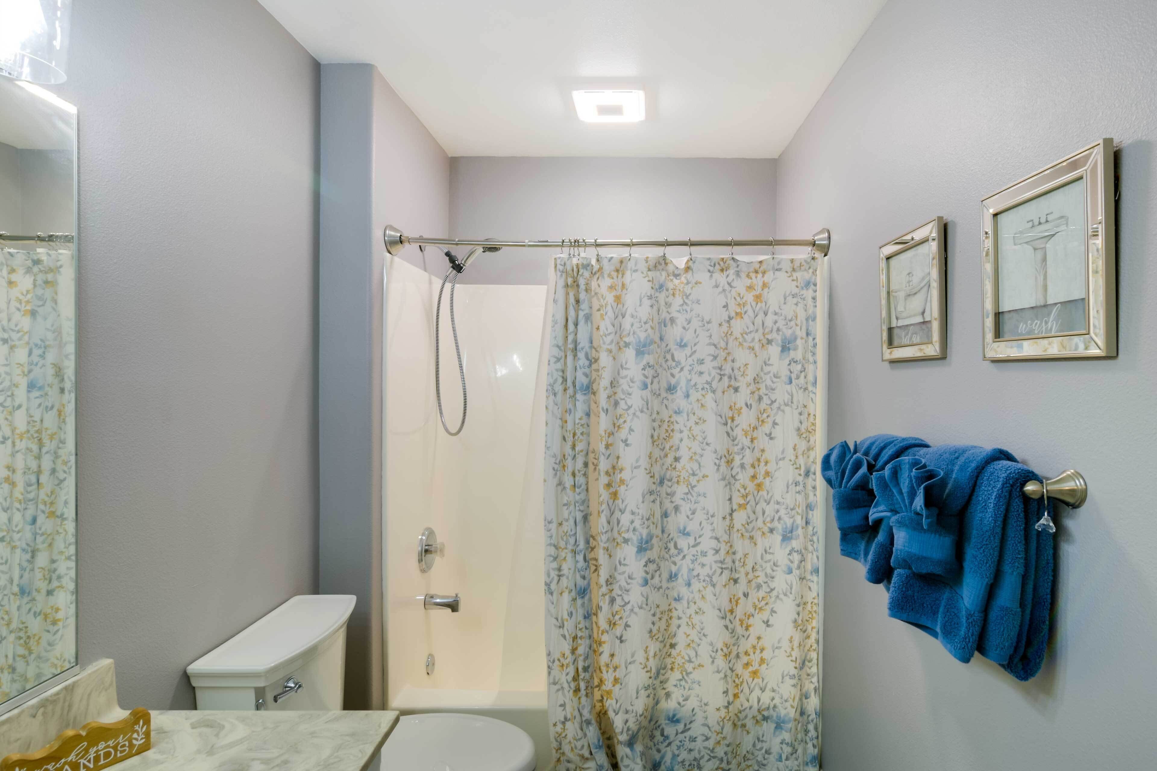 Een badkamer met een douche, toilet en een handdoekrek met handdoeken.