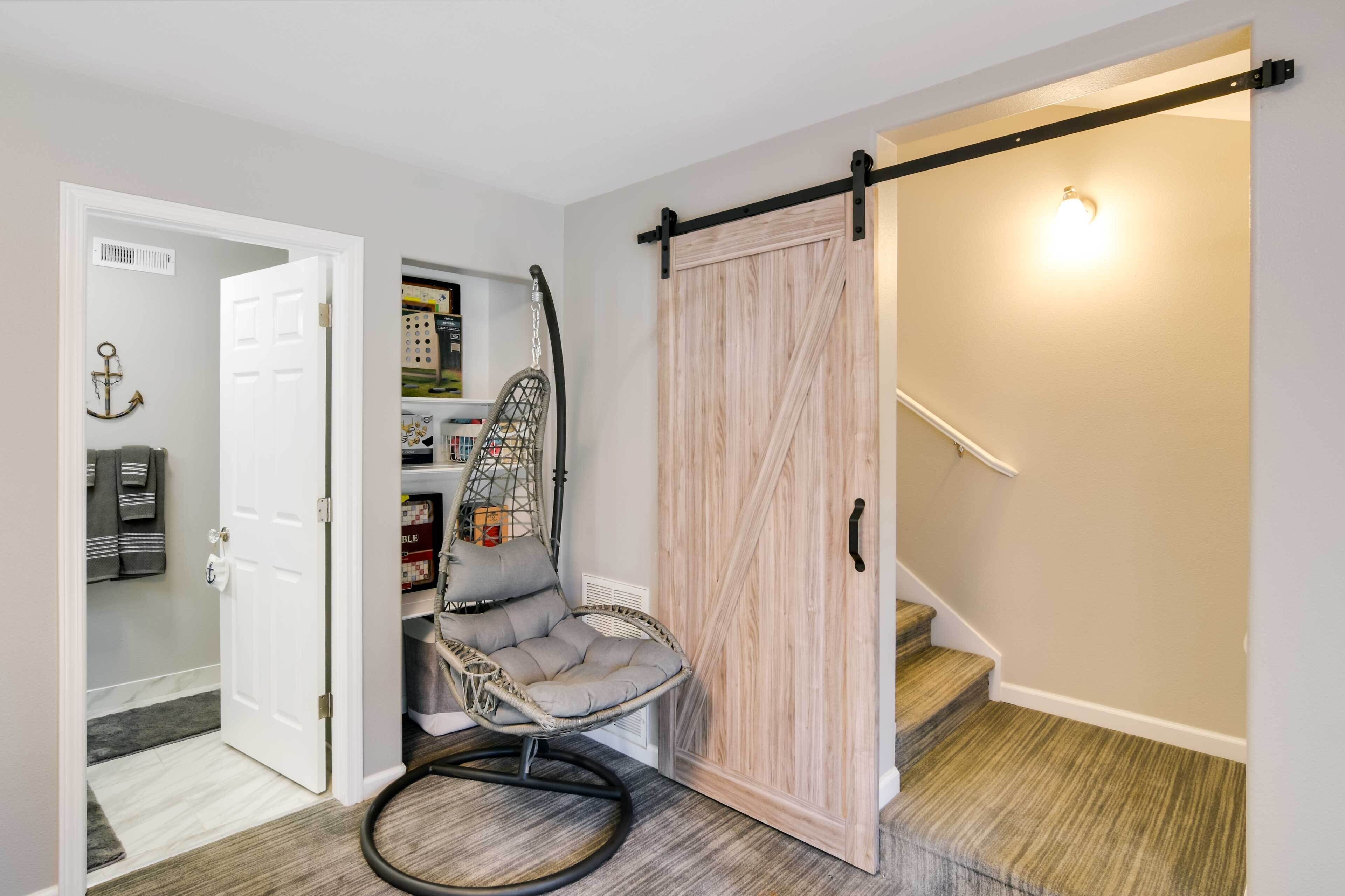A hallway with a white door, a wicker chair, a wooden sliding door, and a staircase.