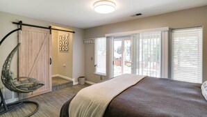 Quarto com cama, cadeira suspensa, porta de madeira e janela com persianas.