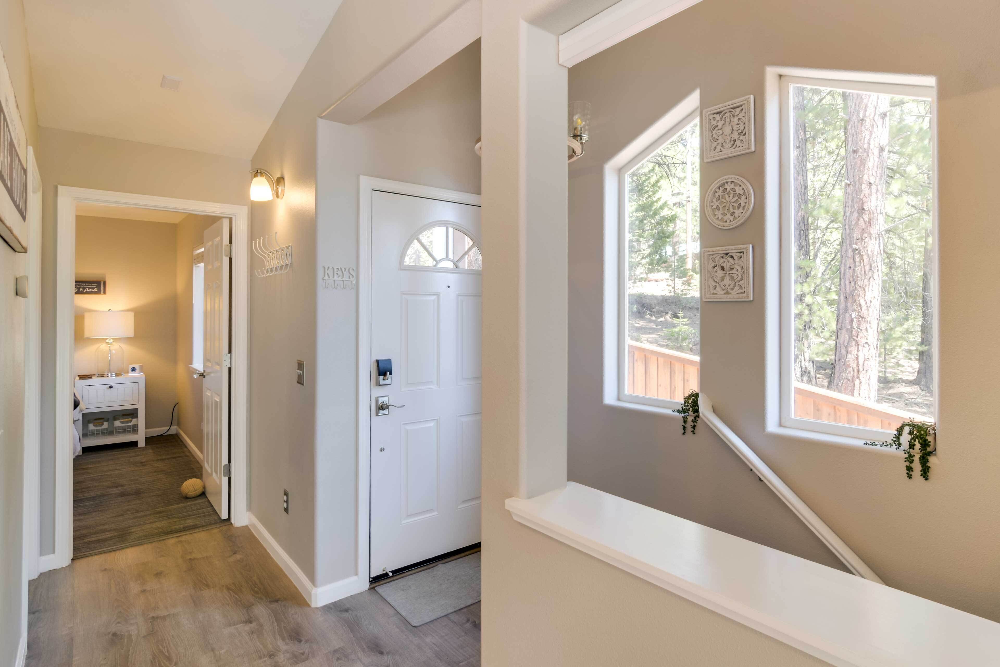 A hallway with a white door, a small table with a lamp, and a window with decorative items.