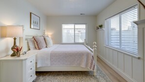 A bedroom with a bed, bedside table, lamp, and a window with blinds. - Orem Vacation Rental w/ Shared Yard & Hot Tub (Orem)