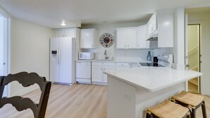 A modern kitchen with white cabinetry, a built-in microwave, and a large island with stools. - Orem Vacation Rental w/ Shared Yard & Hot Tub (Orem)