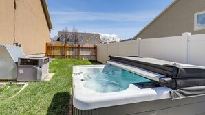 A backyard with a hot tub, a covered patio, and a house in the background. - Orem Vacation Rental w/ Shared Yard & Hot Tub (Orem)
