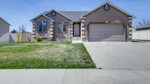 A two-story house with a garage, a front lawn, and a stone facade. - Orem Vacation Rental w/ Shared Yard & Hot Tub (Orem)