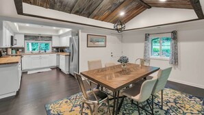 A modern kitchen with white cabinets, a wooden dining table, and a patterned rug. - Pet-friendly Pickens Vacation Rental w/ Fire Pit (Pickens)