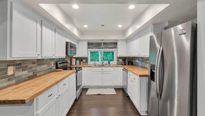 A modern kitchen with white cabinets, a stainless steel refrigerator, and a wooden countertop. - Pet-friendly Pickens Vacation Rental w/ Fire Pit (Pickens)