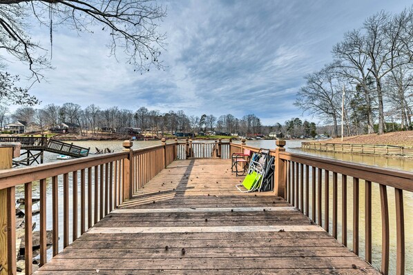 A wooden pier leading to a dock with boats and a bench.