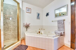 Bathroom features a bathtub, glass shower enclosure, and wooden floor.