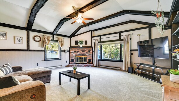 A spacious living room with a fireplace, a ceiling fan, and a large TV. - Cozy Lewiston Home < 10 Mi to Niagara Falls! (Lewiston)