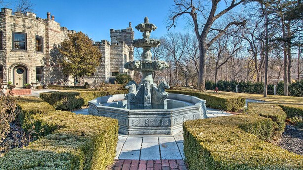 A stone fountain in a landscaped garden with a historic building in the background. - Historic Guest House on Castle Kimble Estate! (Manhattan)