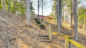 Eine Holztreppe führt einen Hügel hinauf, im Hintergrund ein rotes Gebäude.