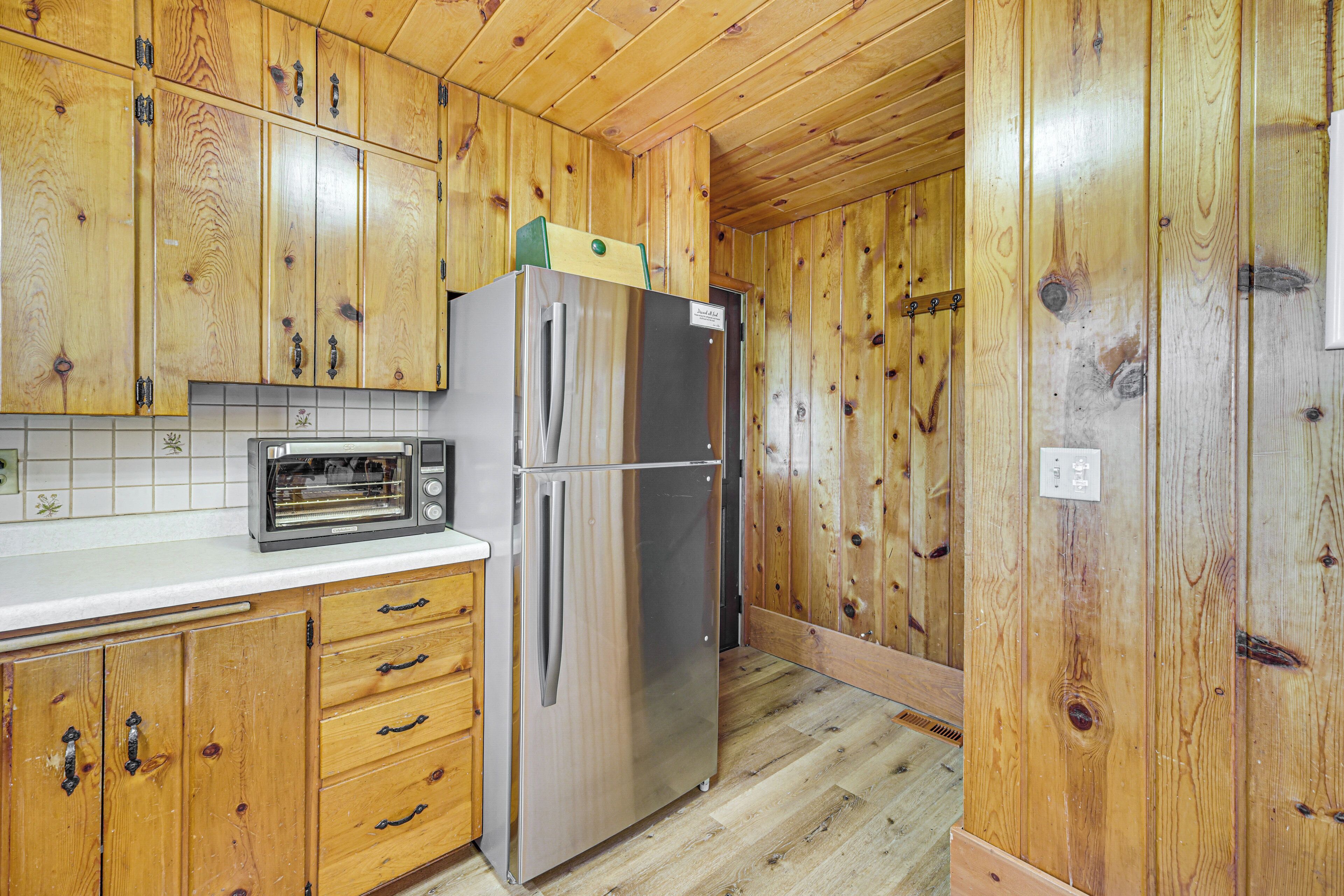 A kitchen with wooden cabinets, a stainless steel refrigerator, and a toaster oven.