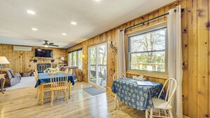 Ein Holzblockhaus-Interieur mit Essbereich, Fernseher und großen Fenstern.