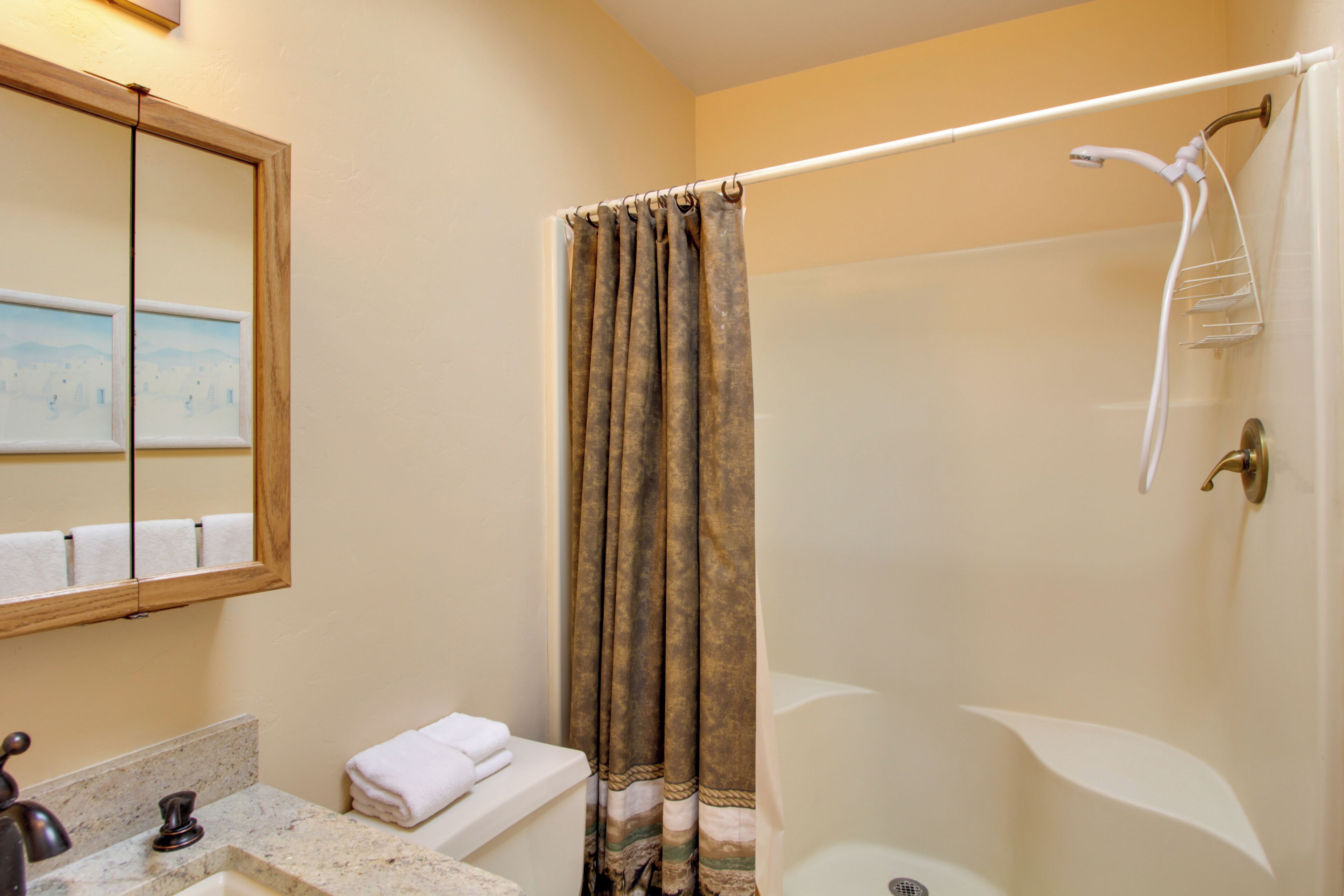 A bathroom with a shower, a sink, and a mirror.